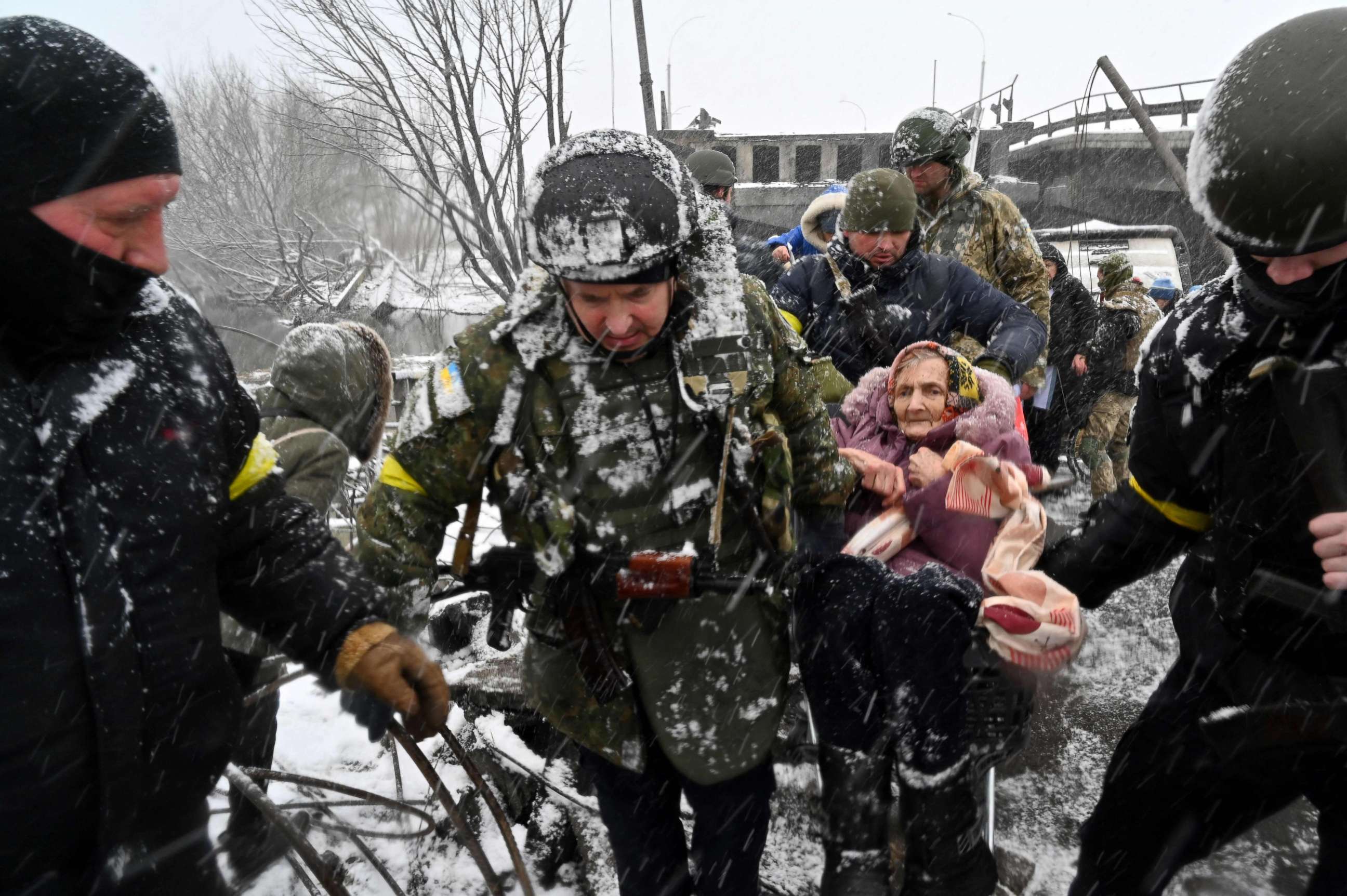 PHOTO: Ukrainian soldiers help an elderly woman to cross a destroyed bridge as she evacuates the city of Irpin, northwest of Kyiv, March 8, 2022.