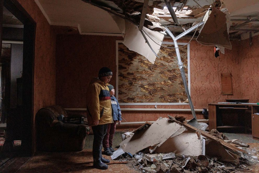 PHOTO: Marat and Renat Bonderenko stand in the living room of their neighbours' house, which was hit by a projectile during an aerial bombardment, in the village of Yakovlivka outside Kharkiv, as Russia's attack on Ukraine continues, April 3, 2022.