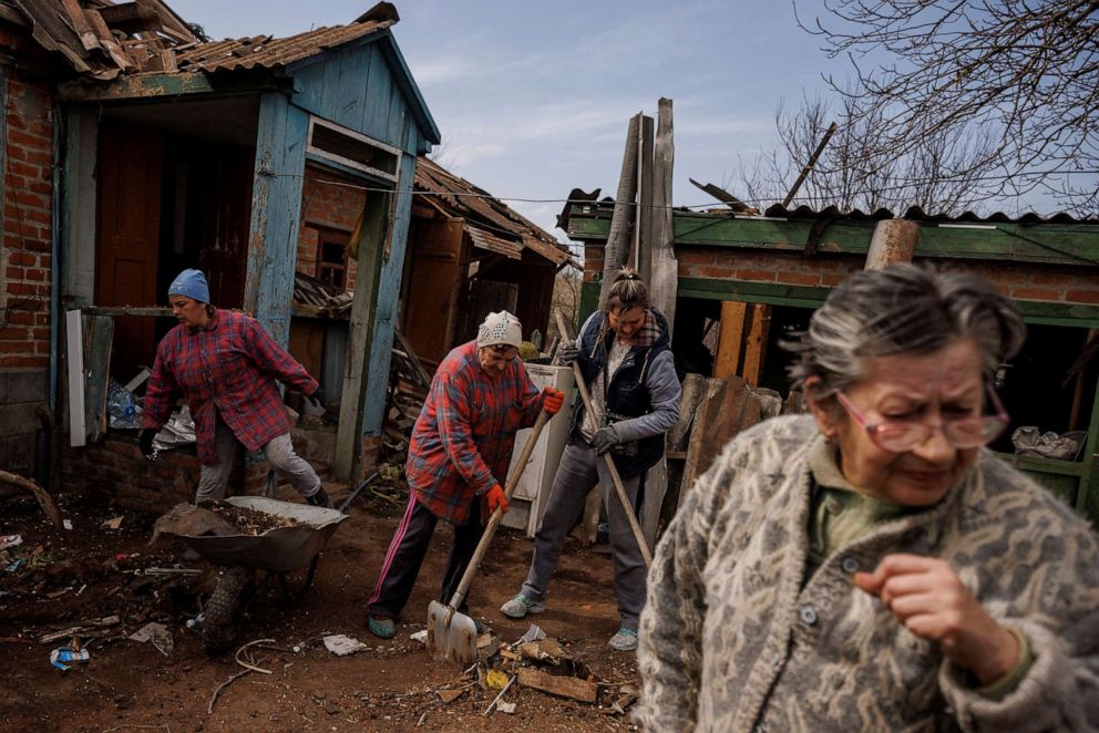 PHOTO: Nina Bonderenko and other locals help their neighbor clean up her yard after an aerial bomb exploded across the street, severely damaging her house, in the village of Yakovlivka outside Kharkiv,  Ukraine, April 2, 2022.