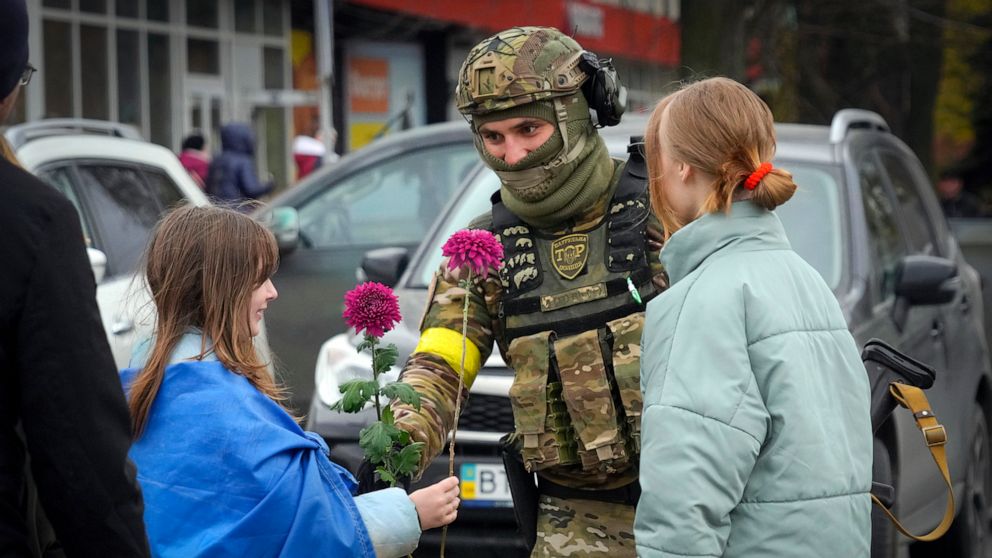 PHOTO: A girl wrapped in the national flag exchange flowers with a Ukrainian soldier in central Kherson, Ukraine, Nov. 13, 2022.