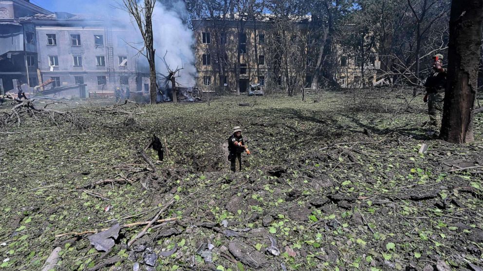 PHOTO: Ukrainian servicemen inspect the hole left after an air strike in the courtyard of hotel Industria and civilian residences in the center of Kramatorsk, July 7, 2022.