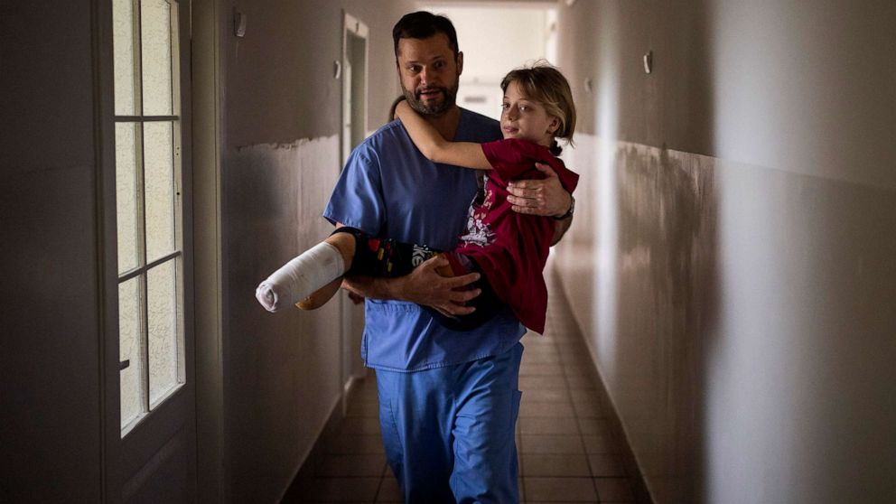 PHOTO: Yana Stepanenko, 11, is carried by a doctor at a hospital in Lviv, Ukraine, May 13, 2022. Yana and her mother Natasha, 43, were injured April 8 during shelling at the Kramatorsk train station where they were trying to evacuate.