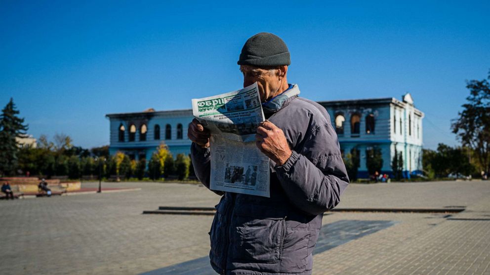 PHOTO: This photo taken on Oct. 18, 2022, shows a local resident reading a newspaper while he waits to receive a food package on the central square in the town of Izyum, amid Russia's invasion of Ukraine.