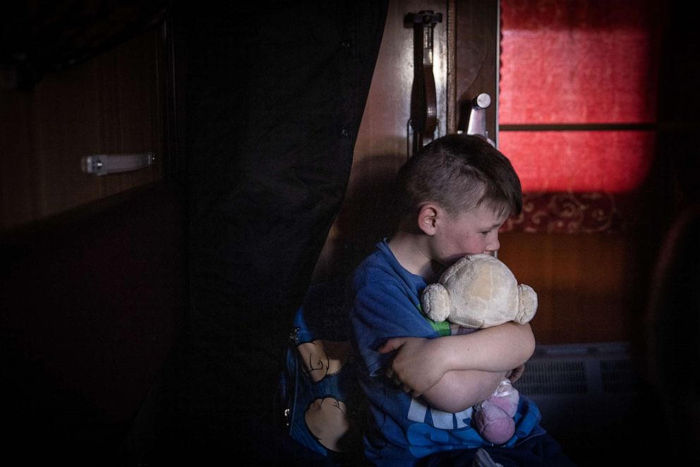 PHOTO: An orphan hugs a soft toy as he waits on a train after fleeing the town of Polohy, which has come under Russian control, before evacuating on a train from Zaporizhzhia to western Ukraine on March 26, 2022.