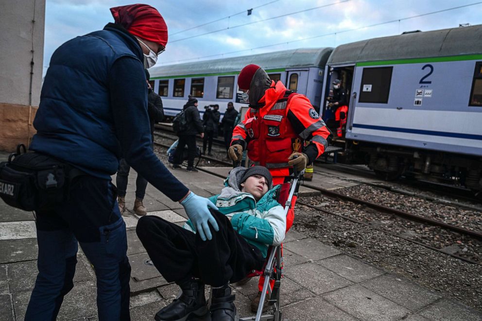 FOTOĞRAF: Polonyalı sağlık görevlileri, 10 Mart 2022'de Polonya'nın Medyka kentinde tıbbi nakil için dönüştürülmüş bir tren vagonuna bir çocuğu taşıyor.