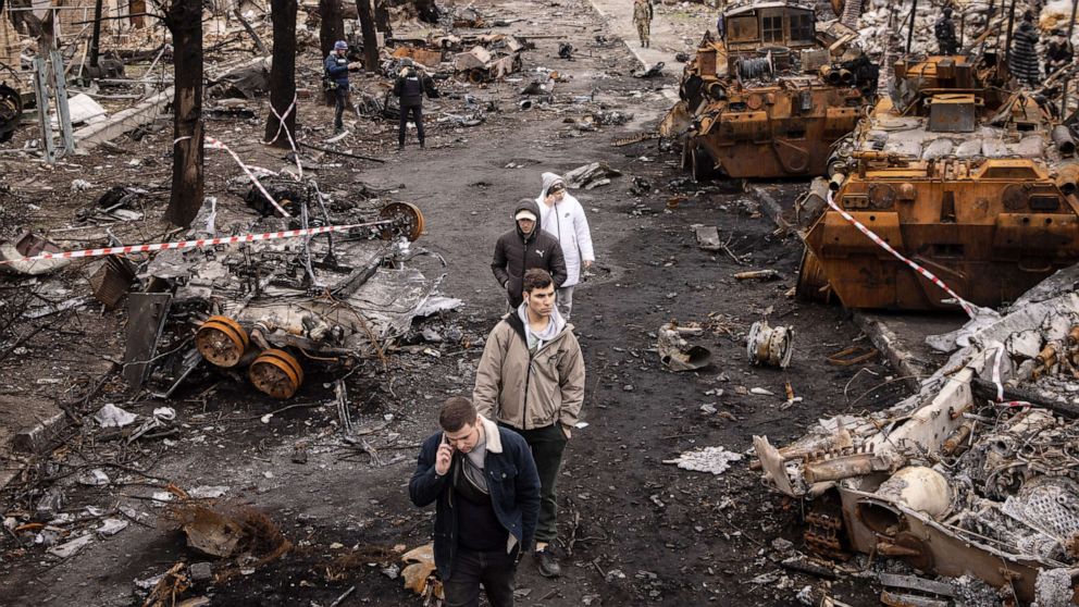 PHOTO: People walk through debris and destroyed Russian military vehicles on a street in Bucha, Ukraine, April 6, 2022.