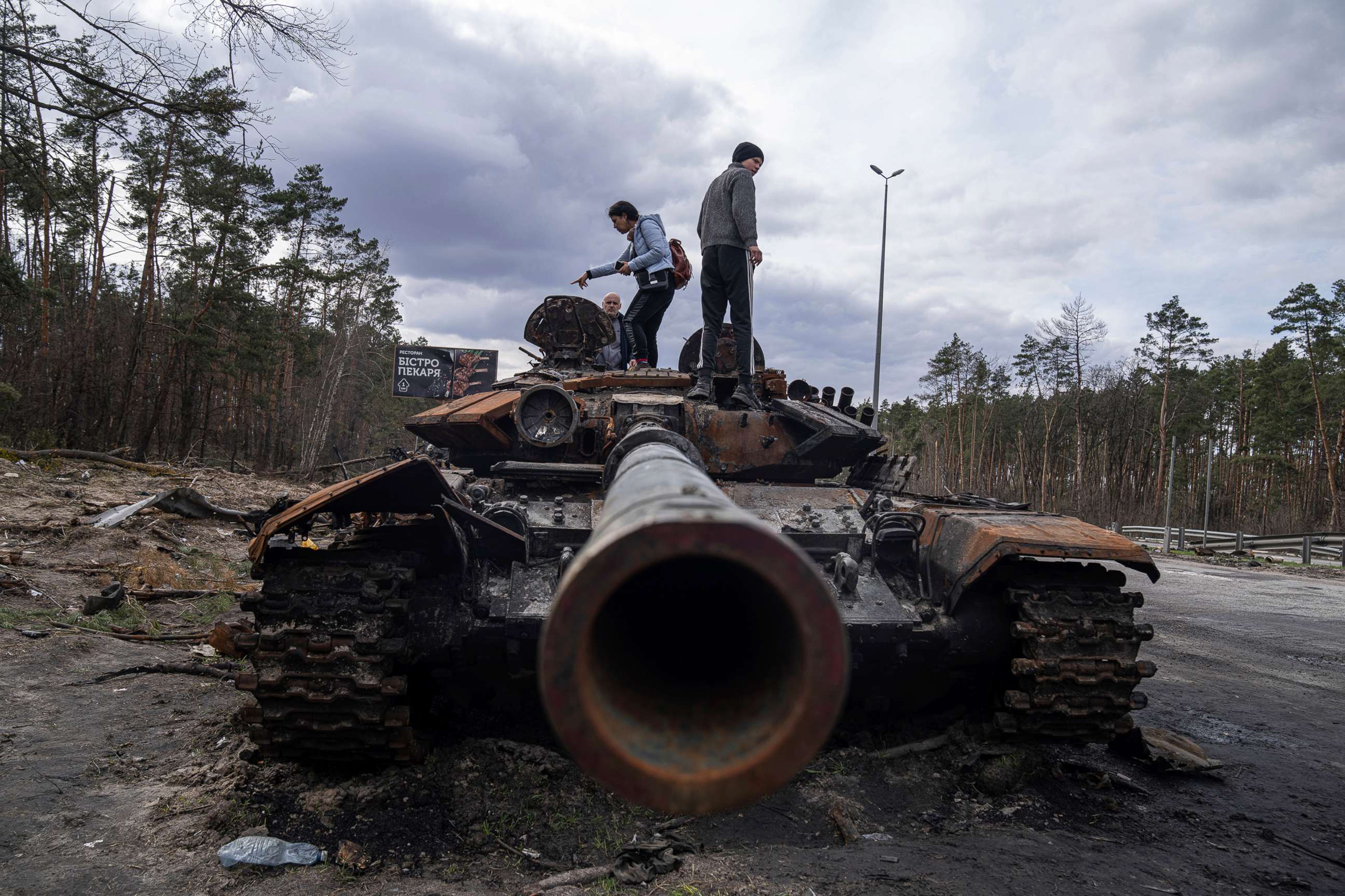 PHOTO: Local residents stand atop of a Russian tank damaged during fightings between Russian and Ukrainian forces in the outskirts of Kyiv, Ukraine, April 11, 2022.
