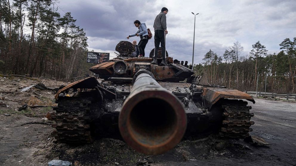 PHOTO: Local residents stand atop of a Russian tank damaged during fightings between Russian and Ukrainian forces in the outskirts of Kyiv, Ukraine, April 11, 2022.