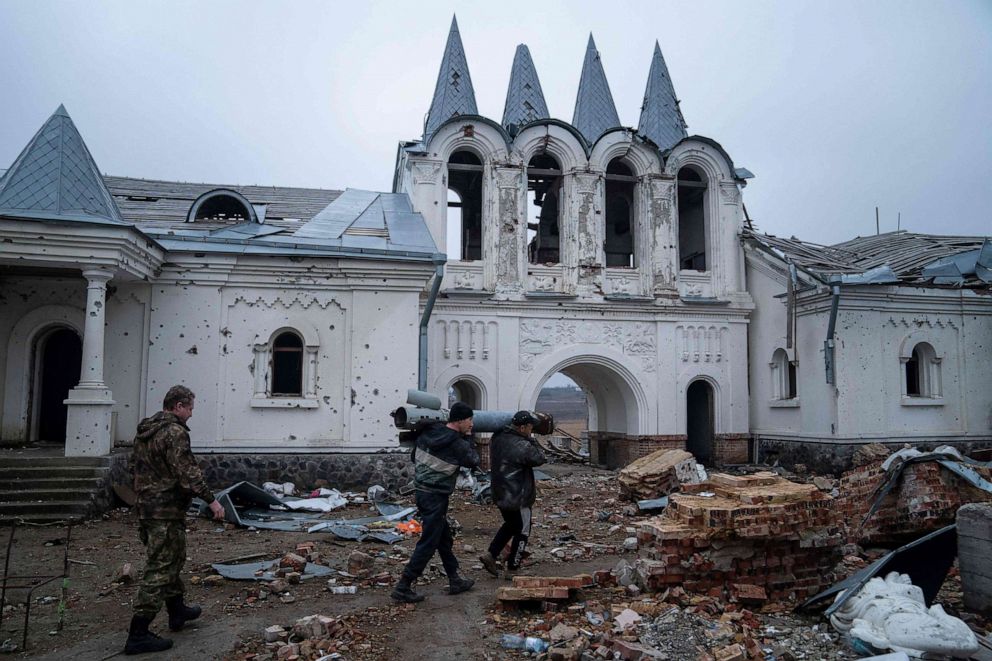 PHOTO: Volunteers carry remains of a Uragan rocket as they clean the area around the Orthodox Svyato-Heorhiyivskyy Skyt of the Sviatohirsk Cave Monastery destroyed in a shelling in the village of Dolyna, Donetsk region, on March 11, 2023.