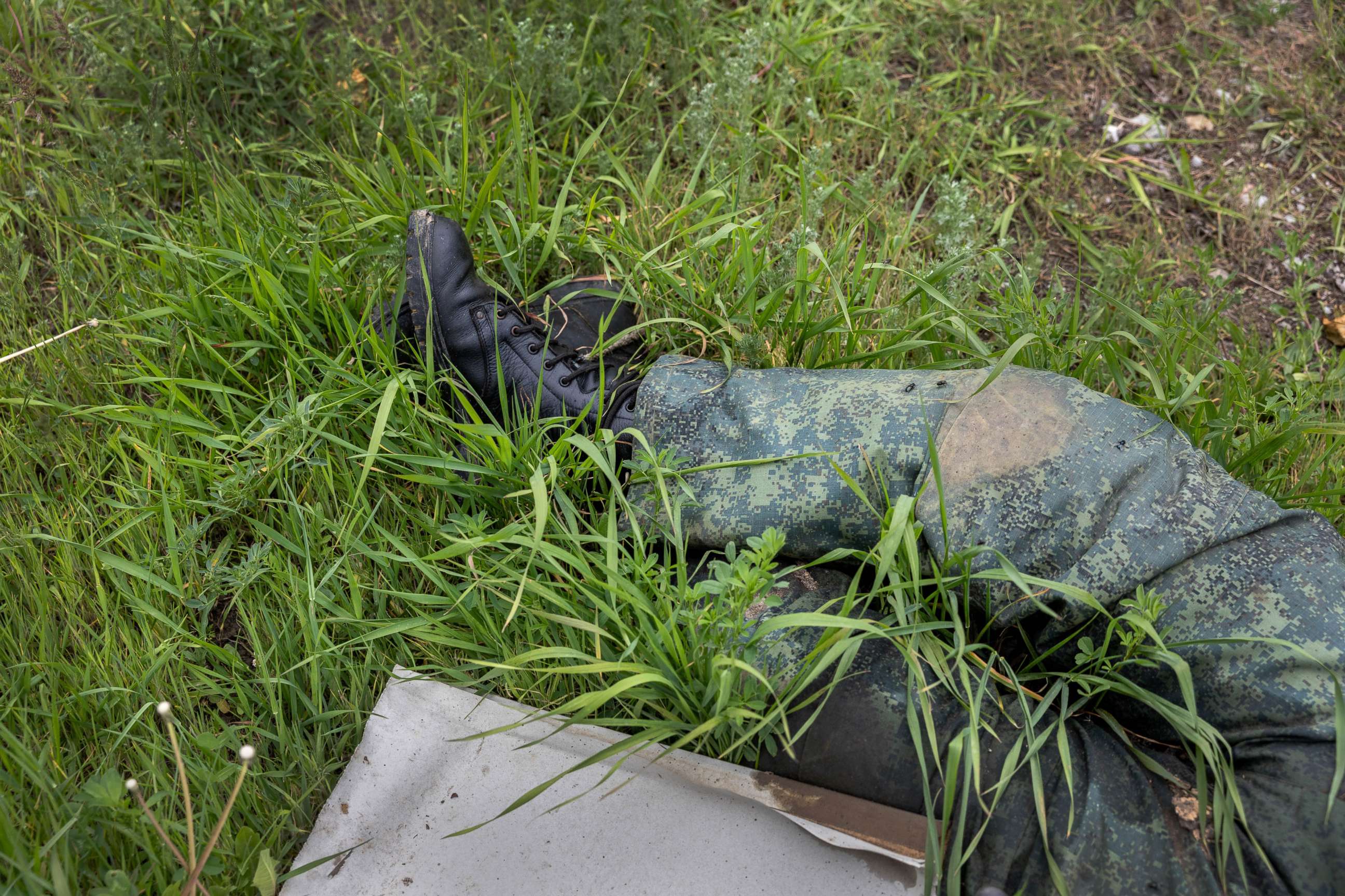 PHOTO: A dead Russian soldier lies next to a destroyed school in Vilkhivka, Ukraine,  May 18, 2022.