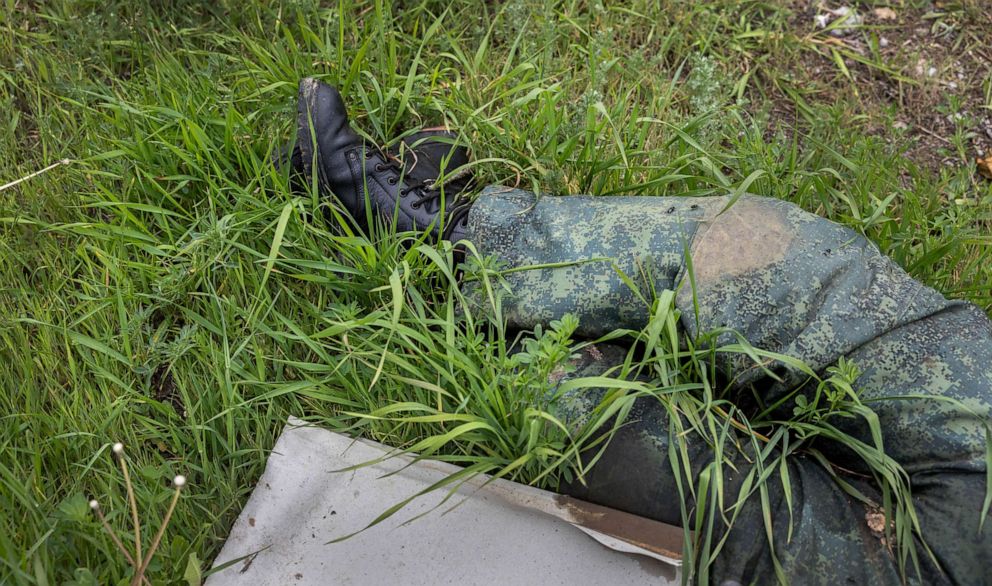 PHOTO: A dead Russian soldier lies next to a destroyed school in Vilkhivka, Ukraine, May 18, 2022.