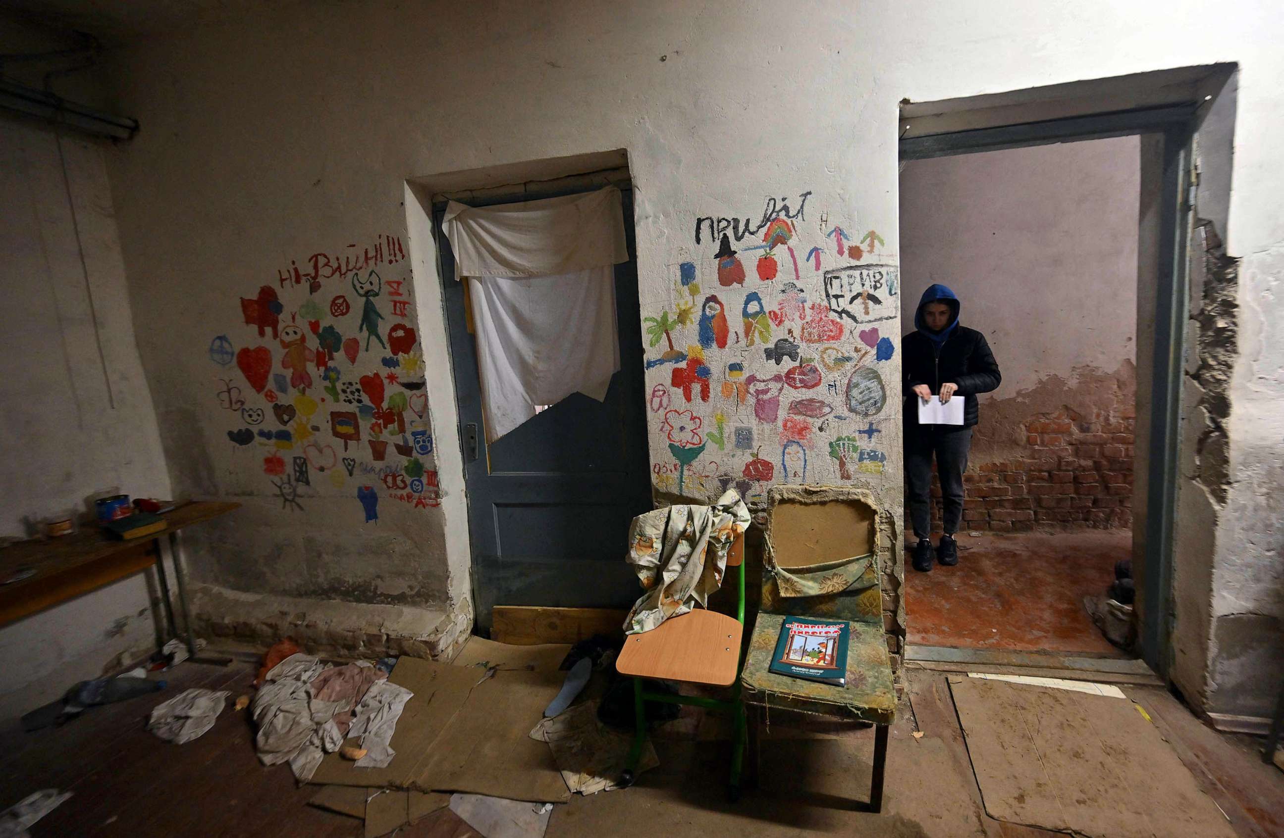 PHOTO: A visitor stands next to children drawings in the basement of a school where villagers were kept for almost a month by Russian troops in the village of Yahidne, north of Kyiv, a year after the liberation of the settlement, April 3, 2023.