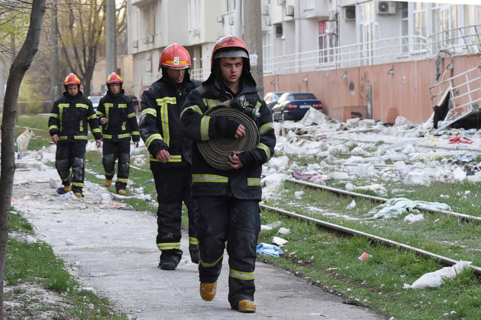 PHOTO: Firefighters walk past an apartment building damaged by Russian shelling in Odesa, Ukraine, April 23, 2022.