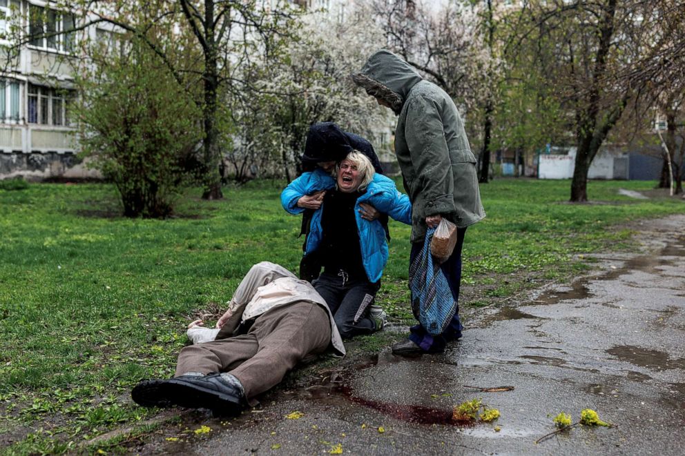 PHOTO: Yana Bachek is consoled by her partner Yevgeniy Vlasenko and her mother Lyubov Gubareva, as she mourns over the body of her father Victor Gubarev, 79, in Kharkiv, Ukraine, April 18, 2022. 