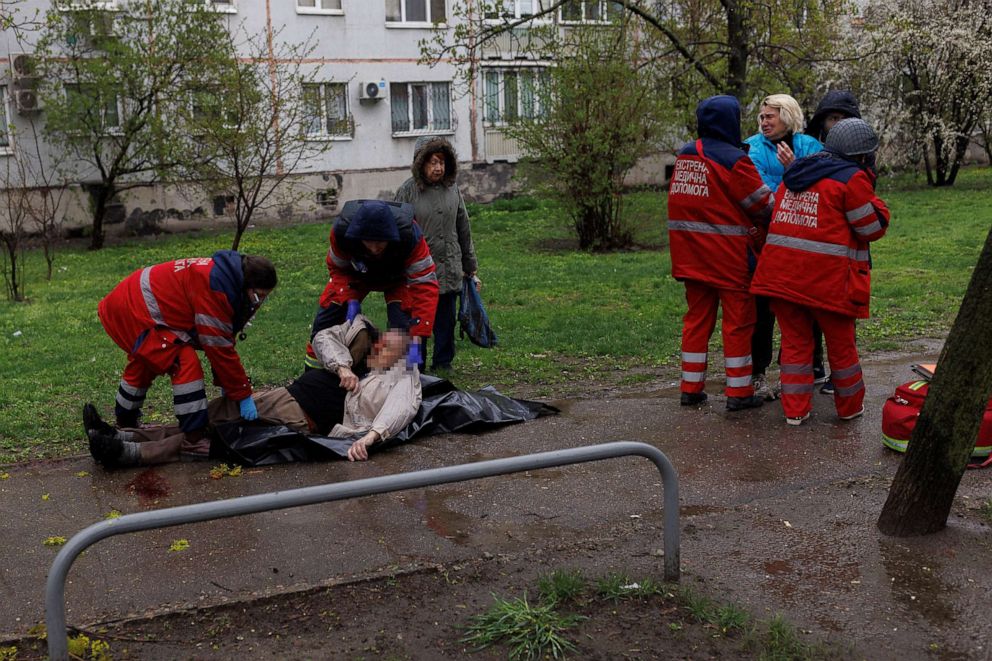 PHOTO: Medical workers retrieve the body of an elderly man Victor Gubarev who was killed by a fragment from a shell that landed in front of his apartment block in Kharkiv, in Ukraine, April 18, 2022.