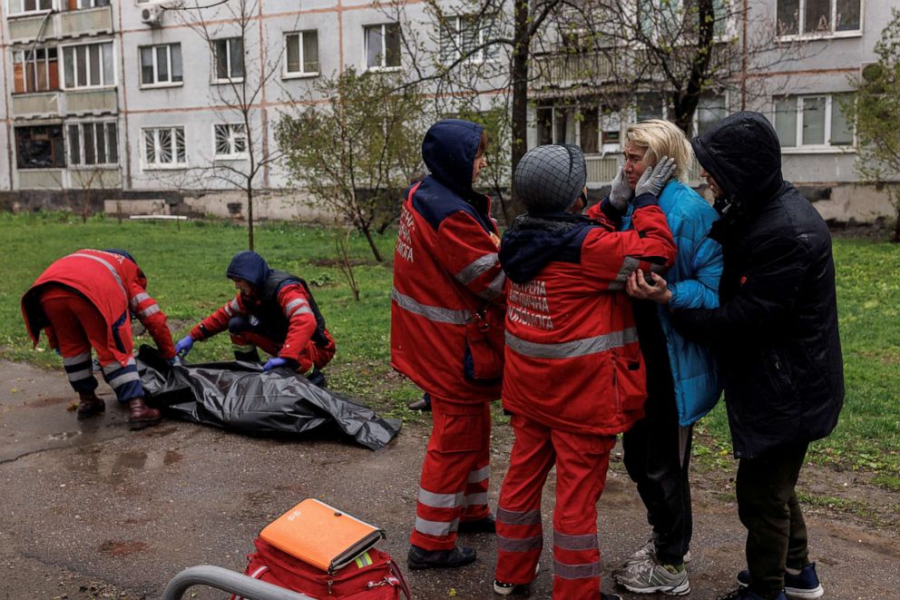 PHOTO: Yana Bachek is consoled by her partner Yevgeniy Vlasenko and a first responder as medical workers retrieve the body of her father Victor Gubarev, in Kharkiv, Ukraine, April 18, 2022.