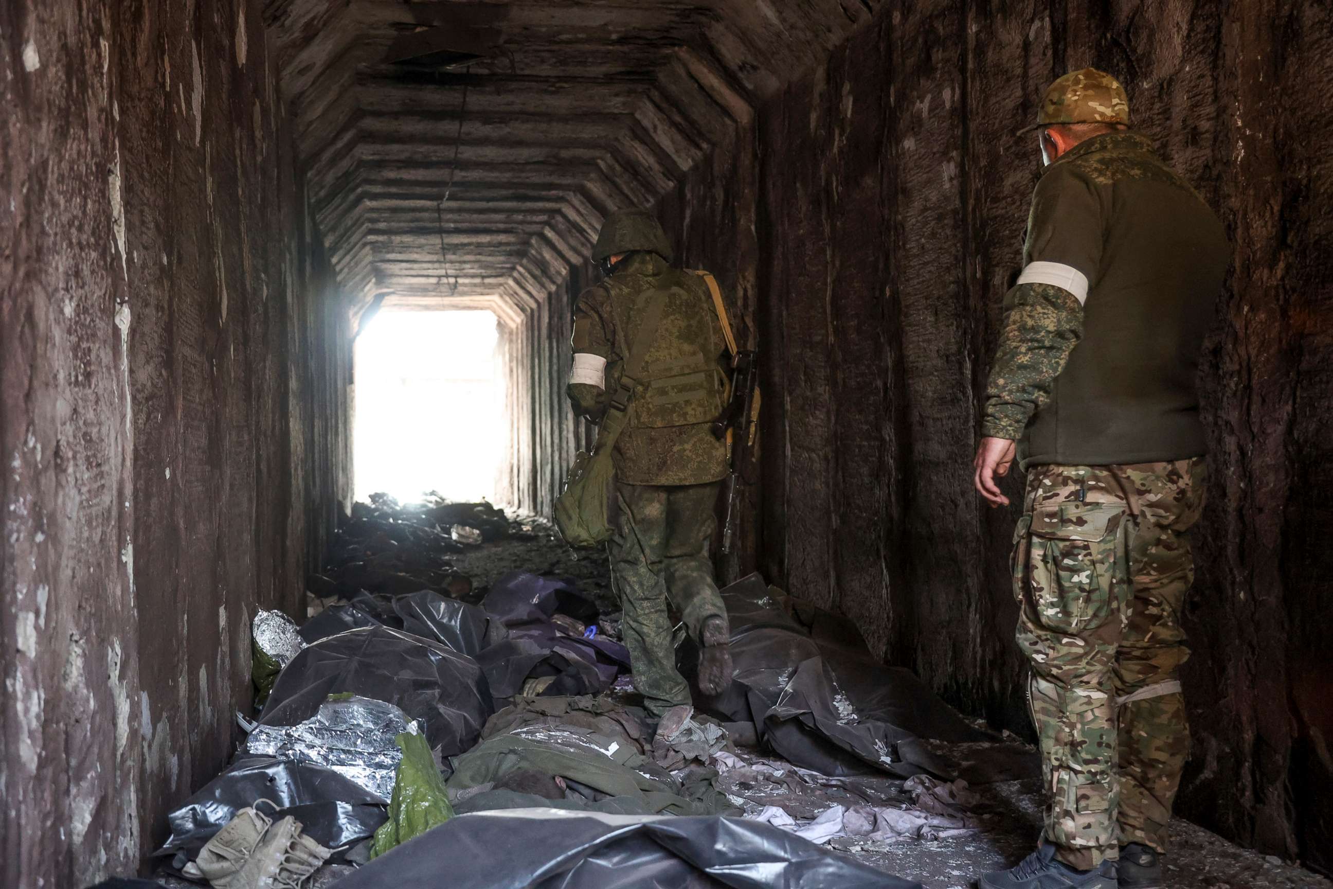 PHOTO: Servicemen of the Donetsk People's Republic militia look at bodies of Ukrainian soldiers placed in plastic bags in a tunnel in an area controlled by Russian-backed separatist forces in Mariupol, Ukraine, April 18, 2022.