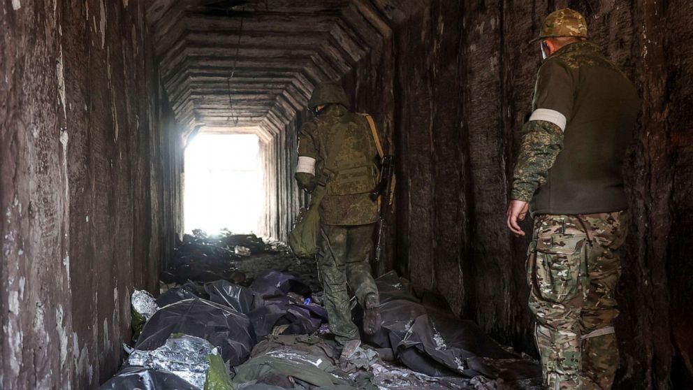PHOTO: Servicemen of the Donetsk People's Republic militia look at bodies of Ukrainian soldiers placed in plastic bags in a tunnel in an area controlled by Russian-backed separatist forces in Mariupol, Ukraine, April 18, 2022.