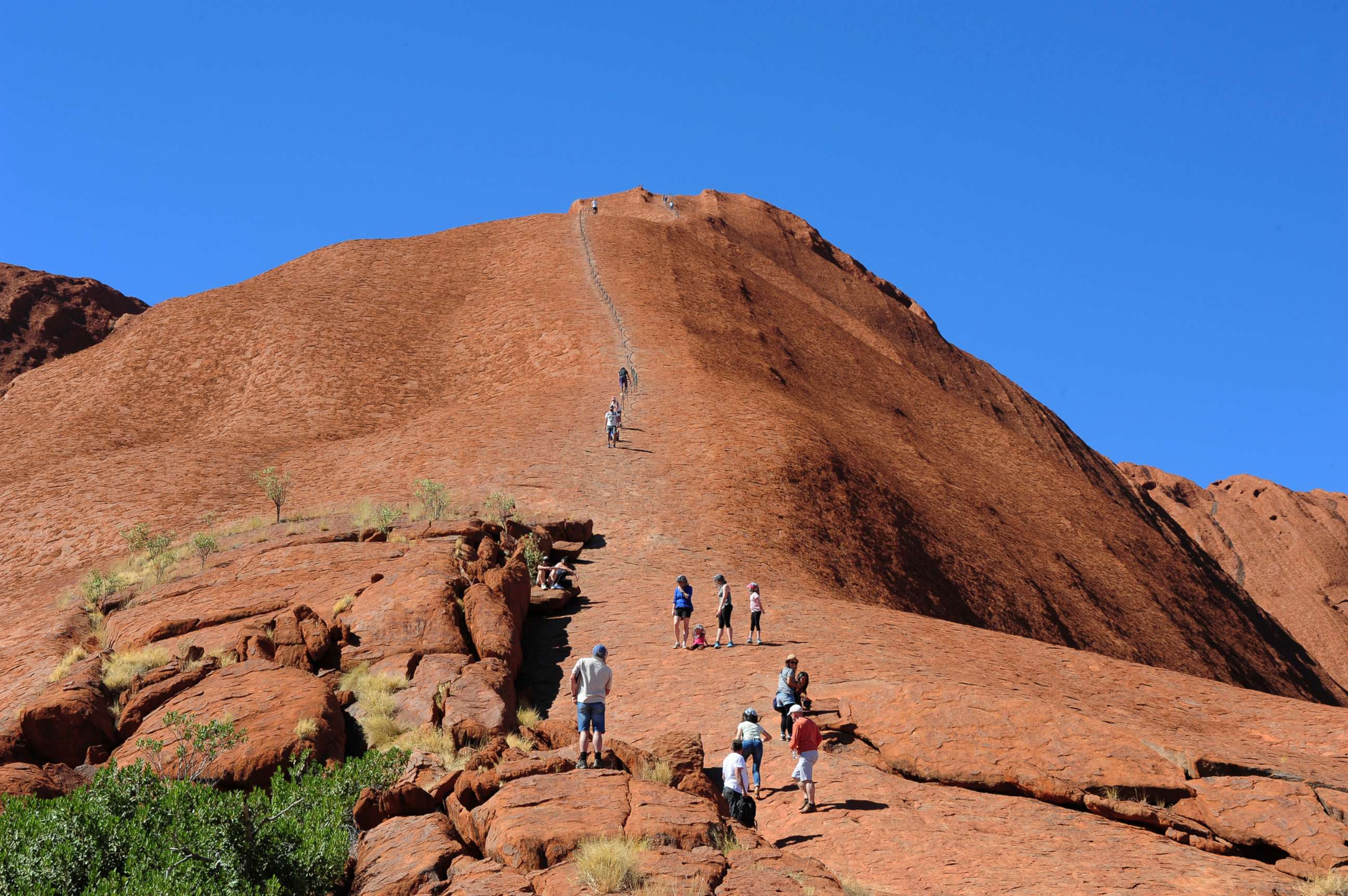 PHOTO: In this file photo, tourists climb on the rock formation of the Uluru in the Uluru Kata Tjuta National Park in Australia, April 15, 2018.
