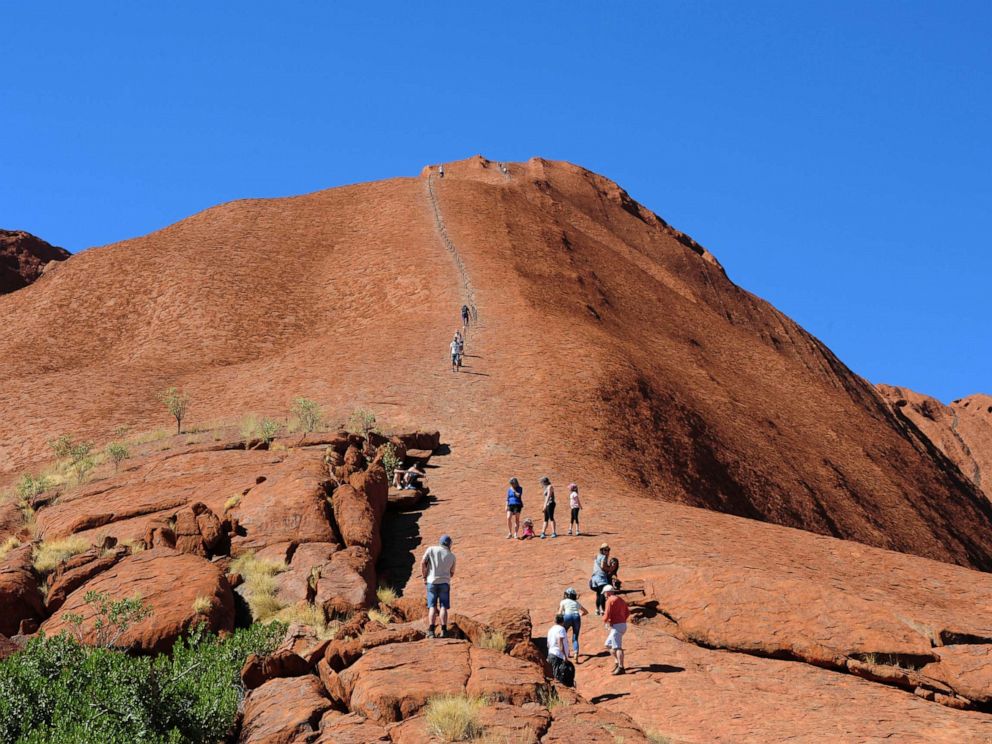 PHOTO: In this file photo, tourists climb on the rock formation of the Uluru in the Uluru Kata Tjuta National Park in Australia, April 15, 2018.