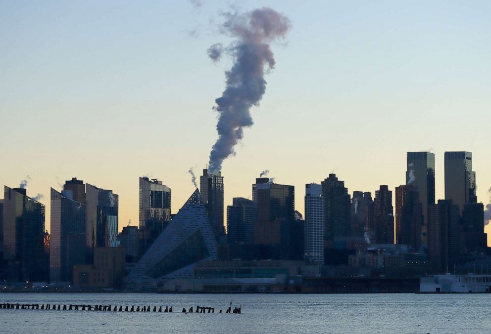 PHOTO: An emission comes out of a smokestack on the west side of Manhattan as the sun rises in New York City on Jan. 16, 2022, as seen from Weehawken, New Jersey.