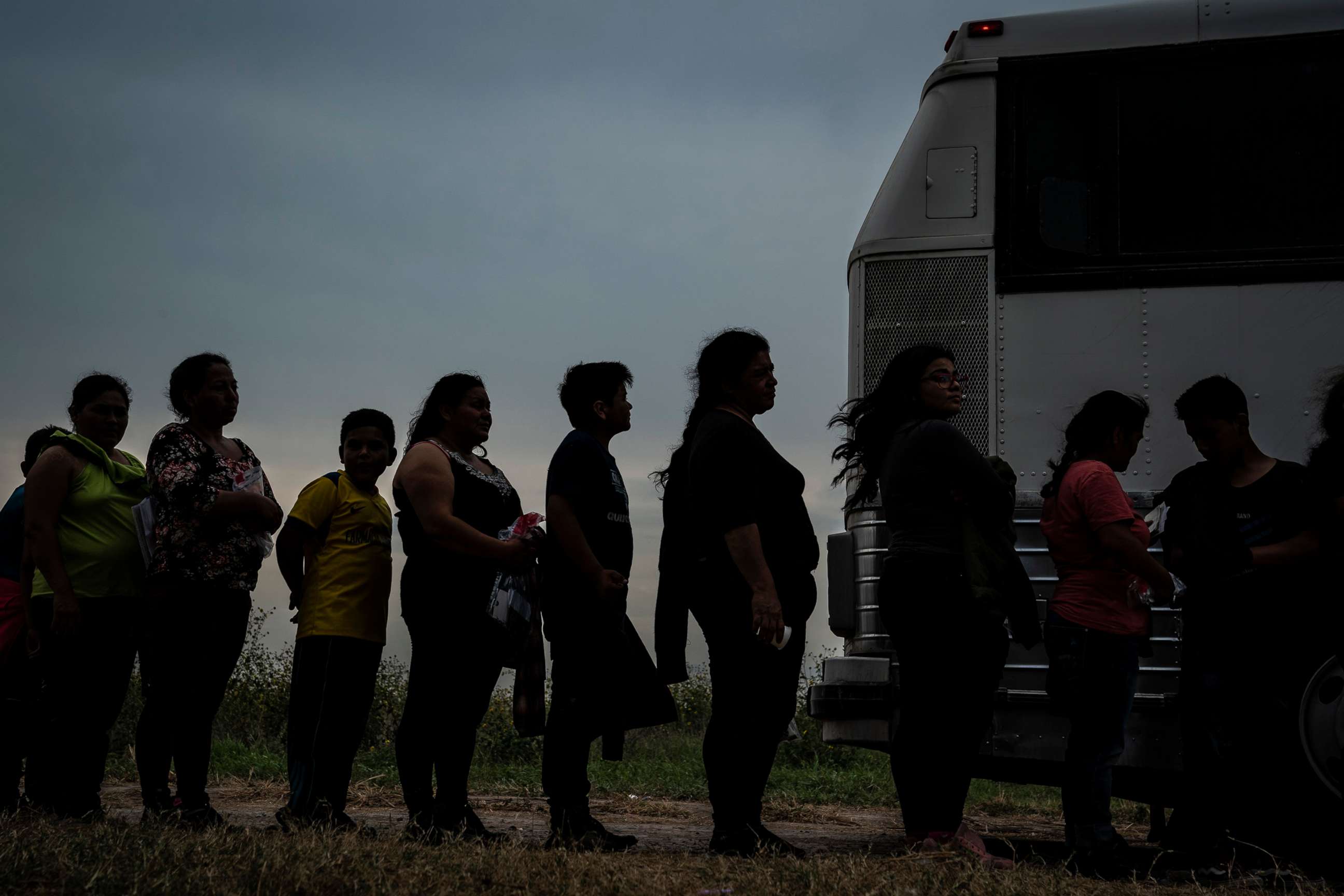 PHOTO: Immigrant families wait to be searched and loaded into transport vans and busses taking them to the U.S. Border Patrol McAllen Station in Los Ebanos, Texas. May 29, 2022.