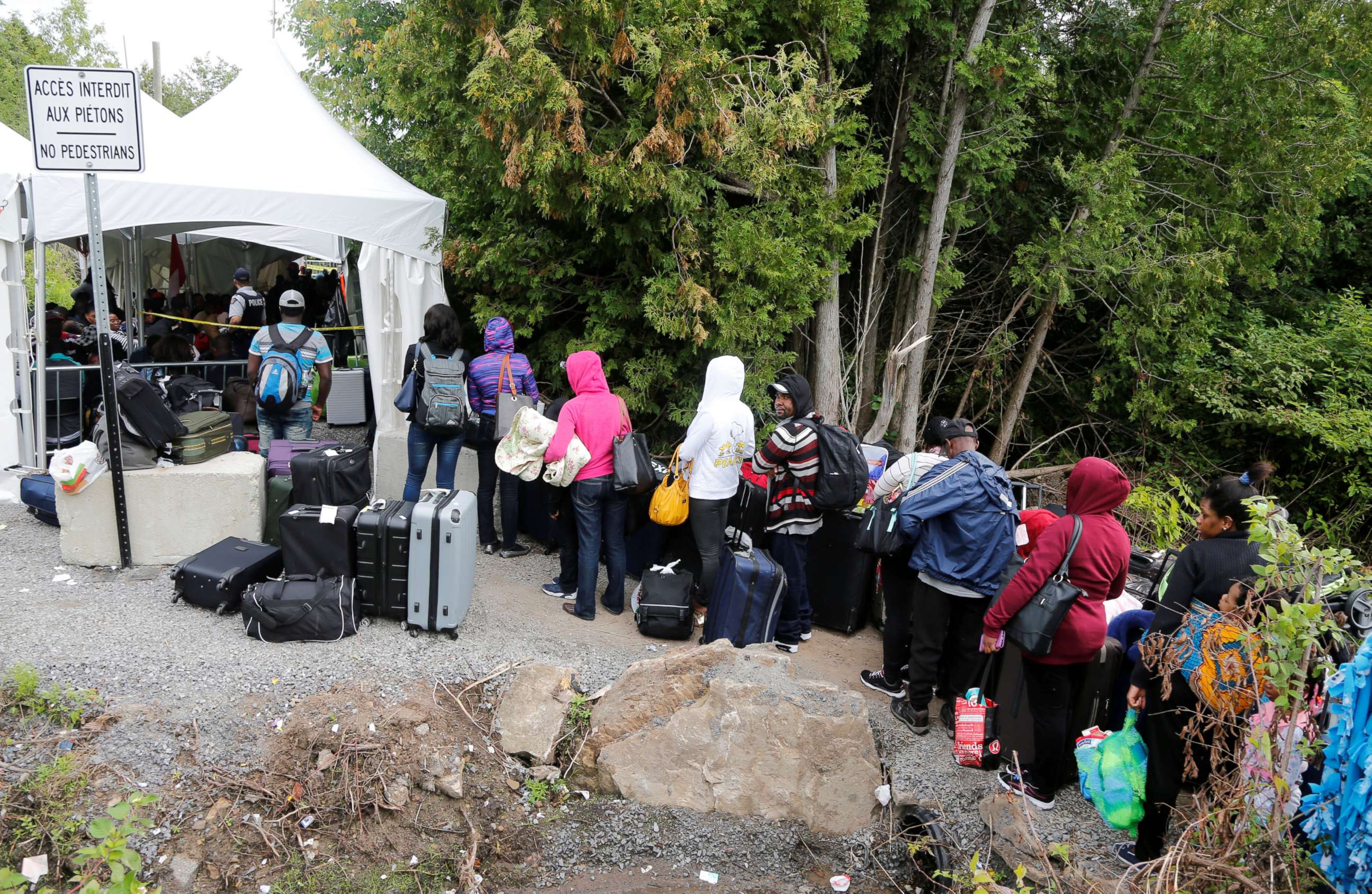 PHOTO: A line of asylum seekers who identified themselves as from Haiti wait to enter into Canada from Roxham Road in Champlain, New York, Aug. 7, 2017.