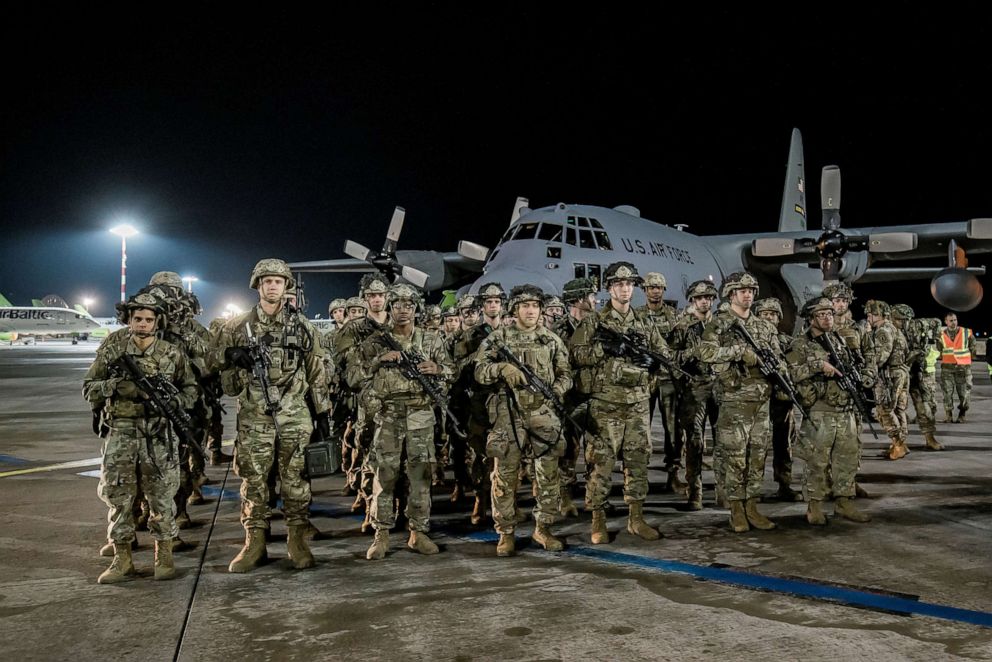PHOTO: U.S. military stand on the tarmac of Riga International Airport as they arrive in Latvia, Feb. 24, 2022.