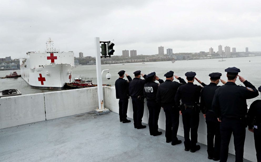 PHOTO: Police officers salute as the U.S. Navy hospital ship USNS Comfort as it departs Pier 90 in Manhattan under thick fog to return to its home port of Norfolk, Va., April 30, 2020.