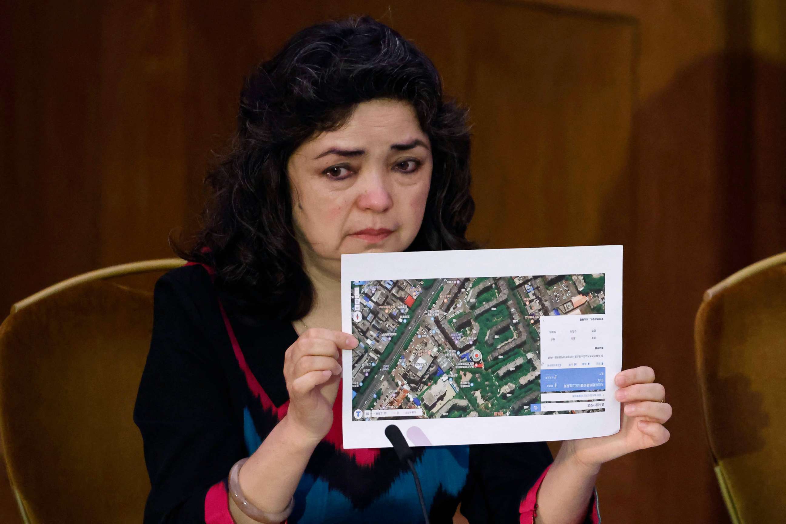 PHOTO: Witness Qelbinur Sidik holds up a photograph of the hospital where she says she underwent a forced sterilization procedure during hearings with lawyers and rights experts investigating abuses against Uyghurs in China, June 4, 2021, in London.