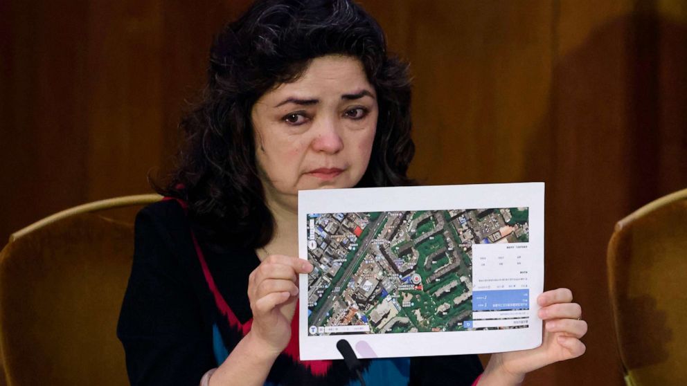 PHOTO: Witness Qelbinur Sidik holds up a photograph of the hospital where she says she underwent a forced sterilization procedure during hearings with lawyers and rights experts investigating abuses against Uyghurs in China, June 4, 2021, in London.