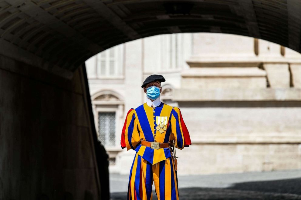 PHOTO: A member of the Vatican Swiss Guard wearing a face mask stands guard by St. Peter's Basilica as it reopens in Vatican City on May 18, 2020, during the lockdown aimed at curbing the spread of the novel coronavirus.