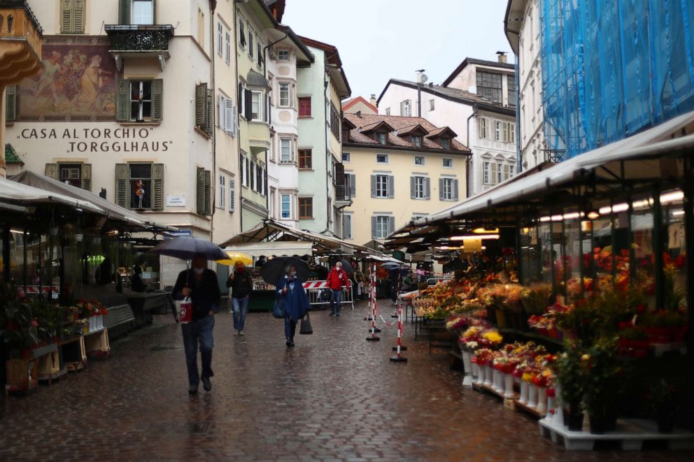 PHOTO: People wearing face masks to protect against the novel coronavirus walk through the traditional vegetable market in Bozen, Italy, on May 11, 2020.