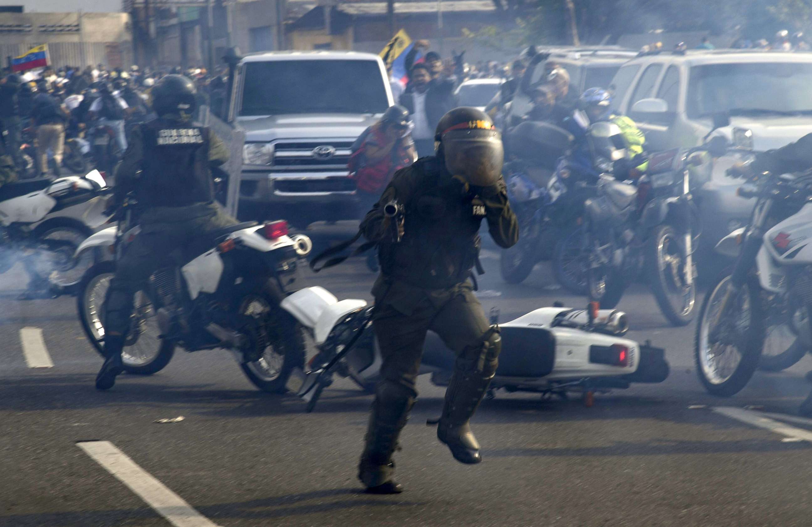 PHOTO:Members of the Bolivarian National Guard run under a cloud of tear gas after being repelled by guards supporting Venezuelan opposition leader Juan Guaido upon arriving to disperse demonstrators, in Caracas, April 30, 2019.