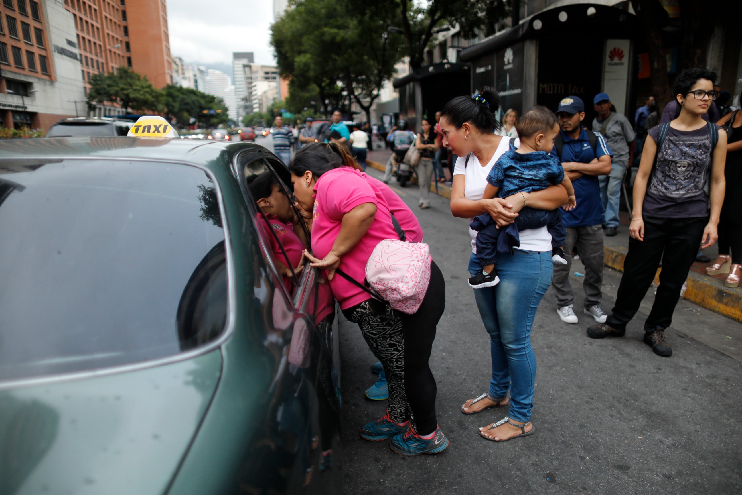 PHOTO: People ask a taxi driver how much it is to take them to their neighborhood during a blackout in Caracas, Venezuela, Monday, July 22, 2019.