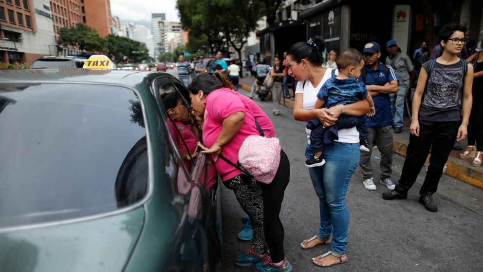 PHOTO: People ask a taxi driver how much it is to take them to their neighborhood during a blackout in Caracas, Venezuela, Monday, July 22, 2019.