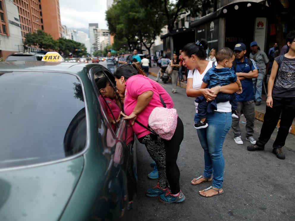 PHOTO: People ask a taxi driver how much it is to take them to their neighborhood during a blackout in Caracas, Venezuela, Monday, July 22, 2019.