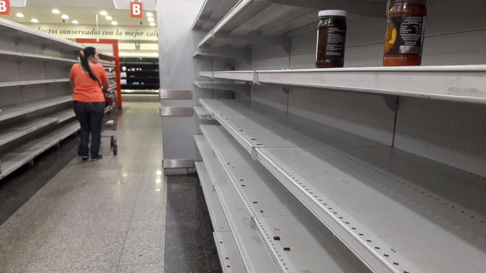 A woman walks between the empty shelves of a supermarket in Caracas, Venezuela, Jan. 11, 2018.