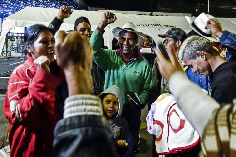 PHOTO: Joel Mendoza, center, and  Edicth Landinez. left, celebrate after obtaining the Andean migration card (TAM), outside the Ecuadoran migrations office at the border between Ipiales, Colombia and Tulcan, Ecuador, Aug. 23, 2018.