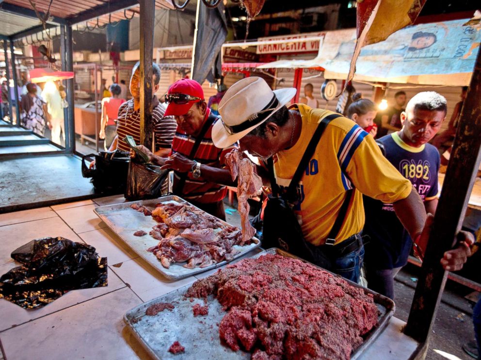 PHOTO: A customer smells a piece of spoiled meat at a market in Maracaibo, Venezuela, Aug. 19, 2018.