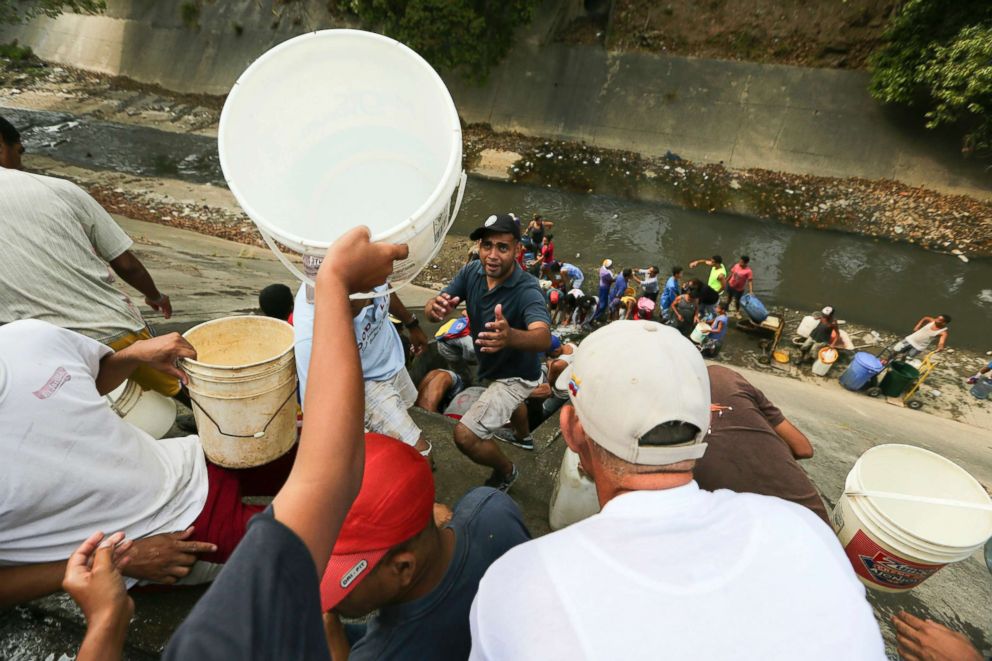 PHOTO: People collect water from a leaking pipeline above the Guaire River during rolling blackouts, which affects the water pumps in people's homes, offices and stores, in Caracas, Venezuela, March 11, 2019.