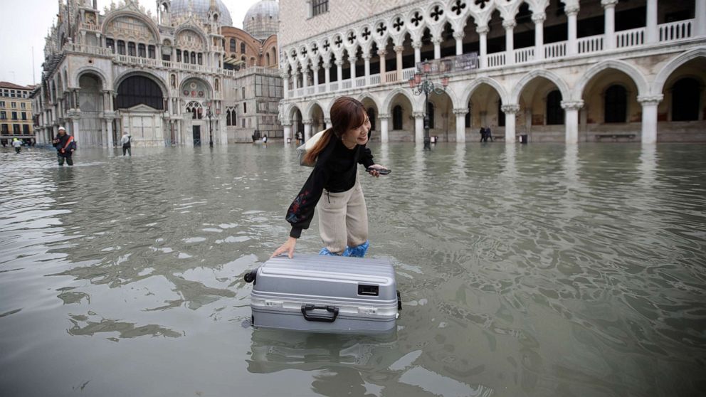 PHOTO: A tourist pushes her floating luggage in a flooded St. Mark's Square, in Venice, Nov. 13, 2019.