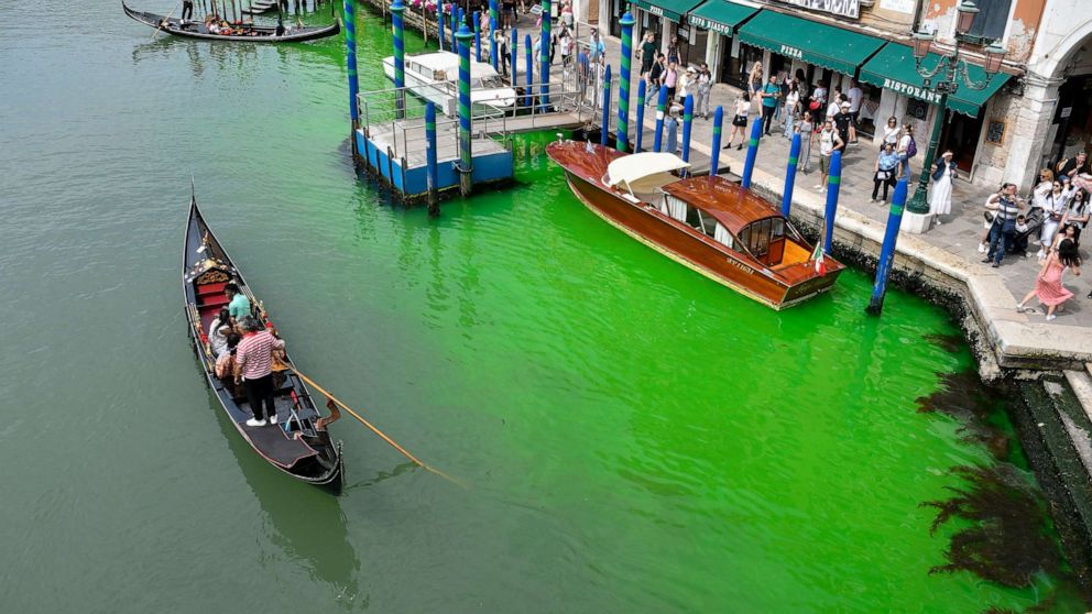 PHOTO: A gondola navigates along Venice's historical Grand Canal as a patch of phosphorescent green liquid spreads in it, May 28, 2023, in Venice, Italy.