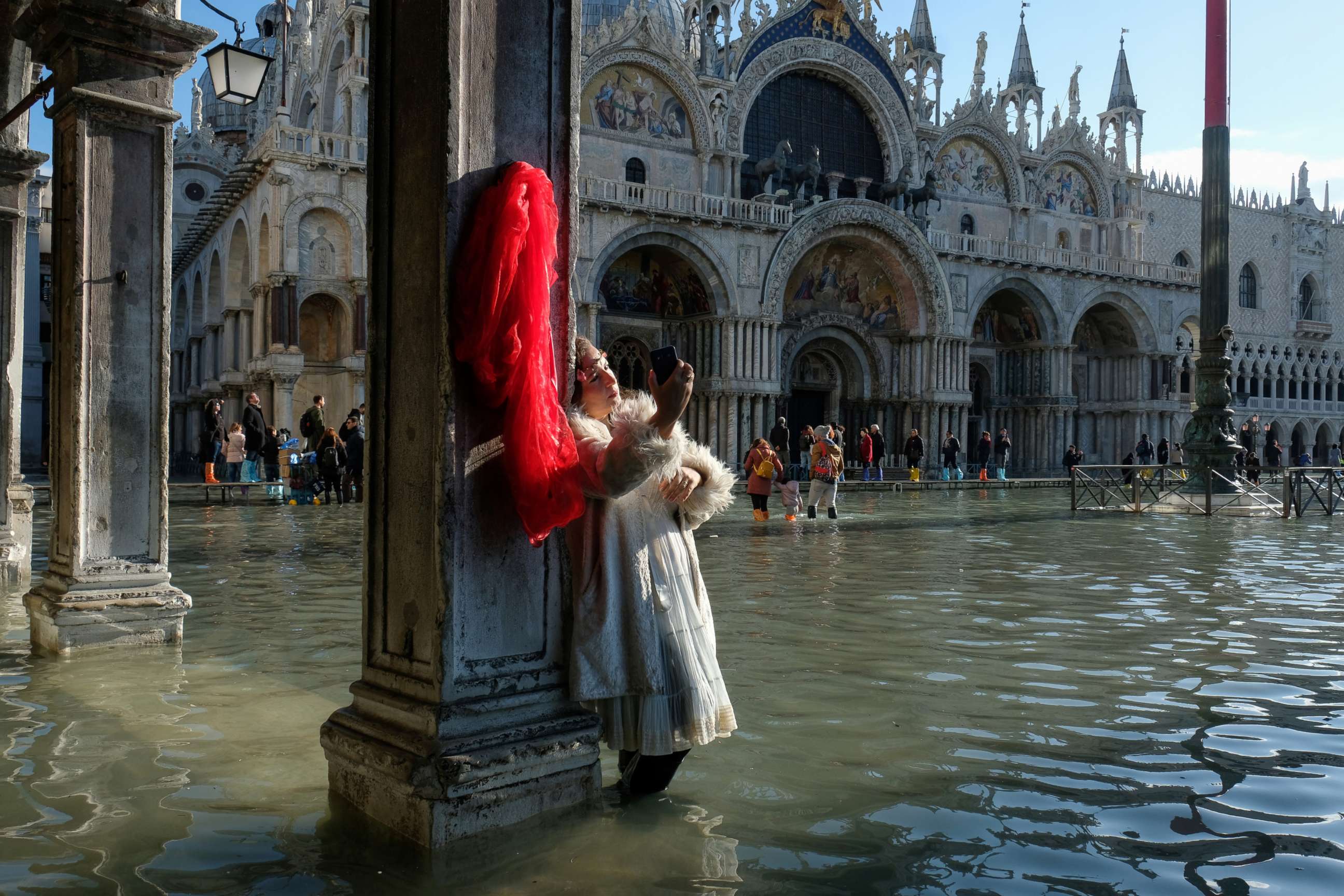 PHOTO: A woman takes pictures in the flooded St. Mark's Square during a period of seasonal high water in Venice, Italy, Nov. 14, 2019.