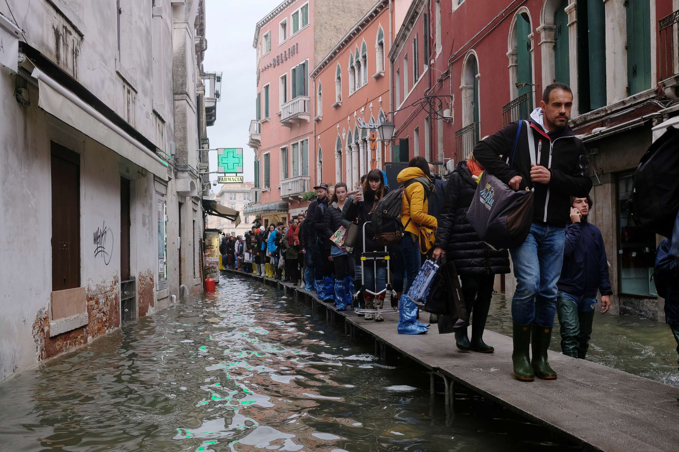 PHOTO: People walk on a catwalk in the flooded street during a period of seasonal high water in Venice, Italy, Nov. 15, 2019.