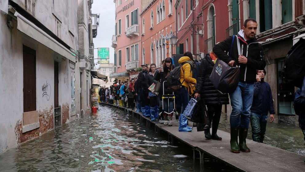 PHOTO: People walk on a catwalk in the flooded street during a period of seasonal high water in Venice, Italy, Nov. 15, 2019.