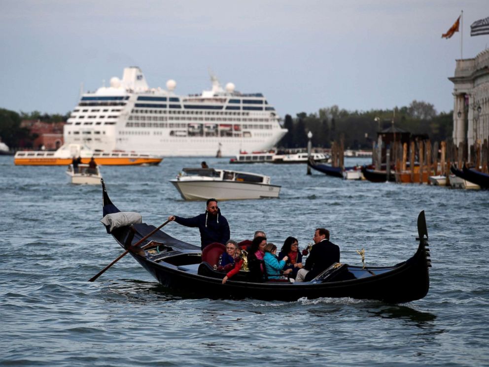 PHOTO: A cruise ship sits in the distance as a gondola with tourists navigates the Grand Canal in Venice on April 7, 2017.