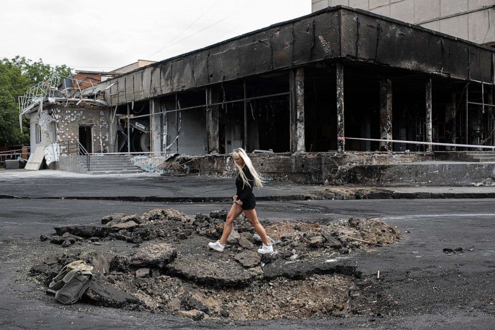 PHOTO: A young woman walks over a hole made by a rocket, July 15, 2022, in Vinnytsia, Ukraine.