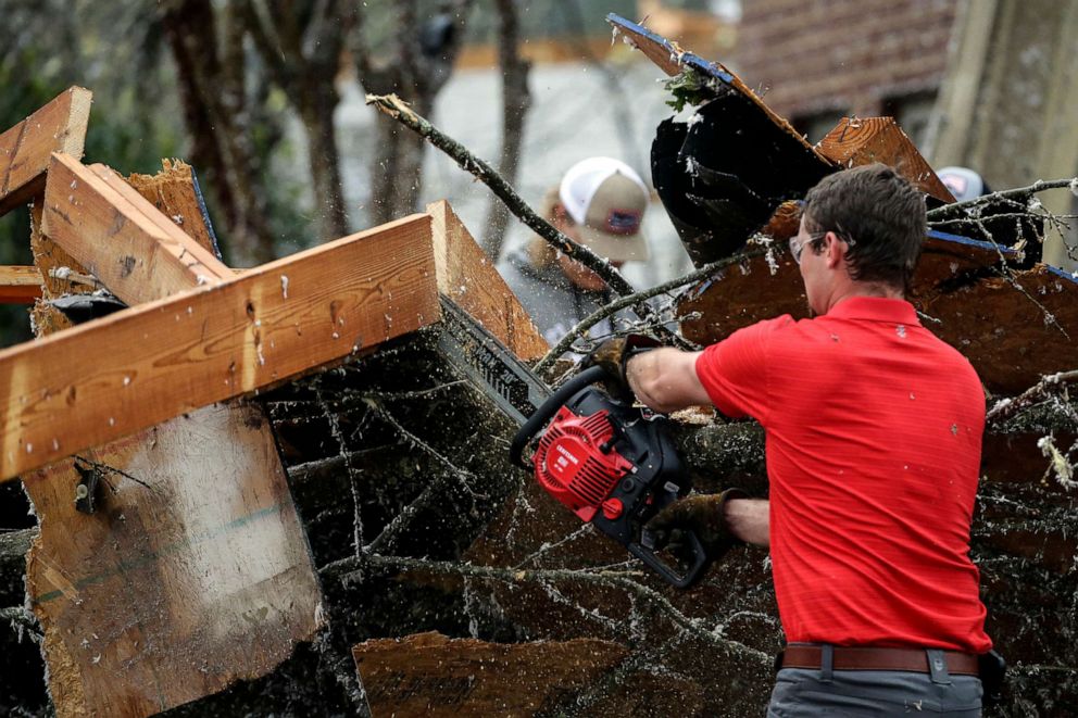 PHOTO: Residents cut away debris after a tornado touches down south of Birmingham, Ala., in the Eagle Point community damaging multiple homes, March 25, 2021.