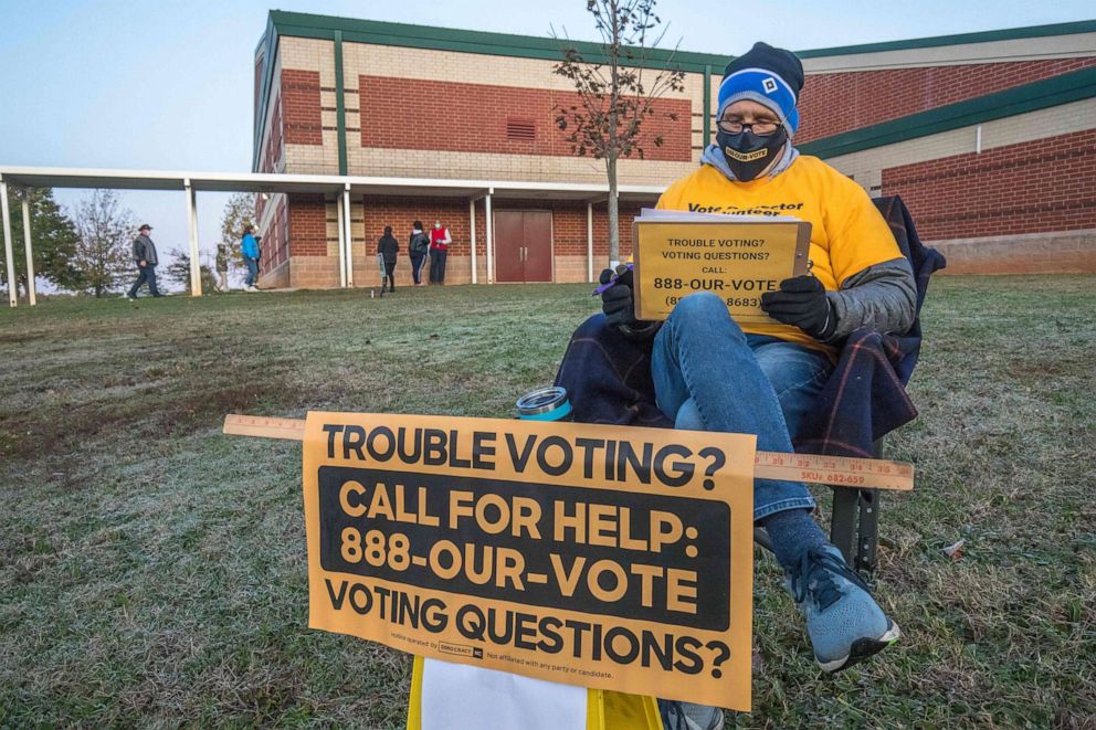 PHOTO: A volunteer with Democracy North Carolina sits to answer questions at Waddell Language Academy in Charlotte, N.C. shortly after the polls opened on election day, Nov. 3, 2020.